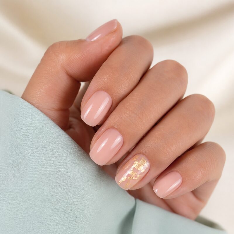 Mano con manicura rosa nude y destellos dorados